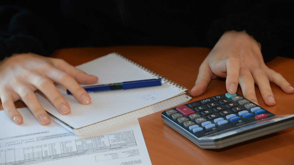 Main avec cahier et calculatrice